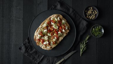PINSA TRADIZIONALE with in garlic marinated cherry tomatoes, burrata, rosemary and pine nuts